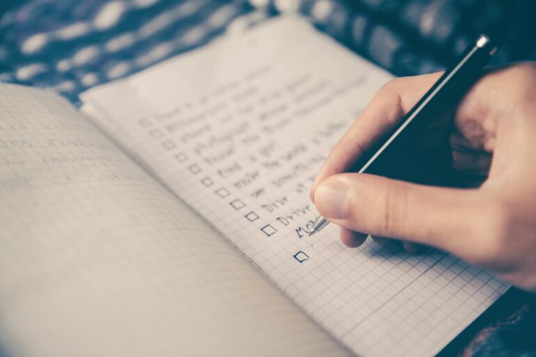 person writing checklist - green home buying checklist