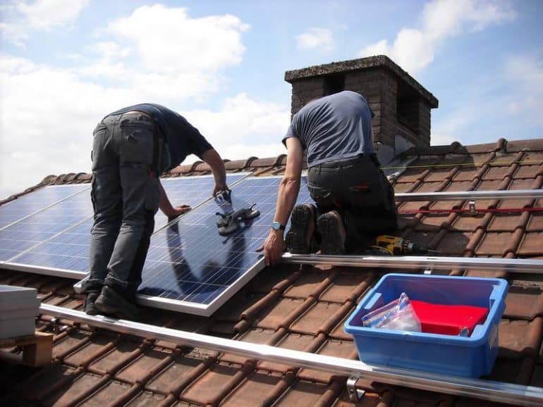 Two people installing solar panels on roof of house - Solar rooftop DIY