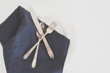 Silver metal cutlery and a navy blue napkin - Ditch the single-use plastics