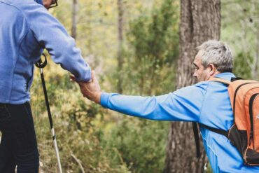 two senior men helping each other on a trail - eco-friendly tips for seniors to follow