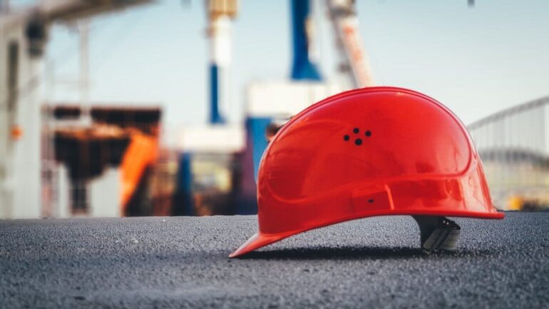 red construction helmet on ground - green building - things to consider before hiring a contractor