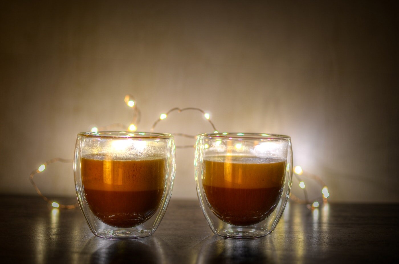 two lattes in glass mugs with fairy lights - fill your home with light and warmth this winter