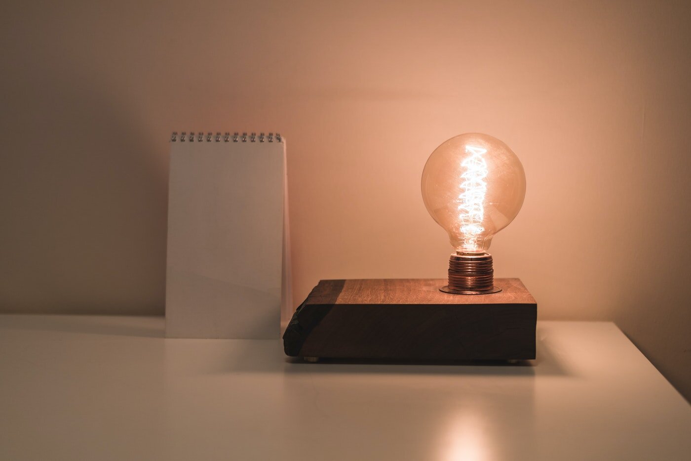 lightbulb on nightstand next to notepad - 10 surefire ways to trim your energy use