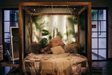 fairy lights strung on wooden bed frame with plants behind - 7 tips to create an eco-friendly bedroom