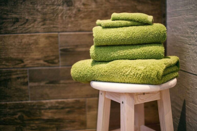 green towels on stool in bathroom - how to create an eco-friendly bathroom retreat