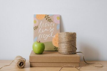 box, string and apple with reduce, reuse, recycle sign - how to be less wasteful at home with zero-waste
