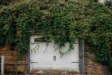 white garage door covered in hanging branches - spring cleaning for a greener garage