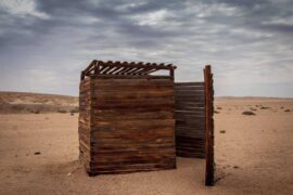 outhouse in desert under grey sky - how to build a diy composting toilet