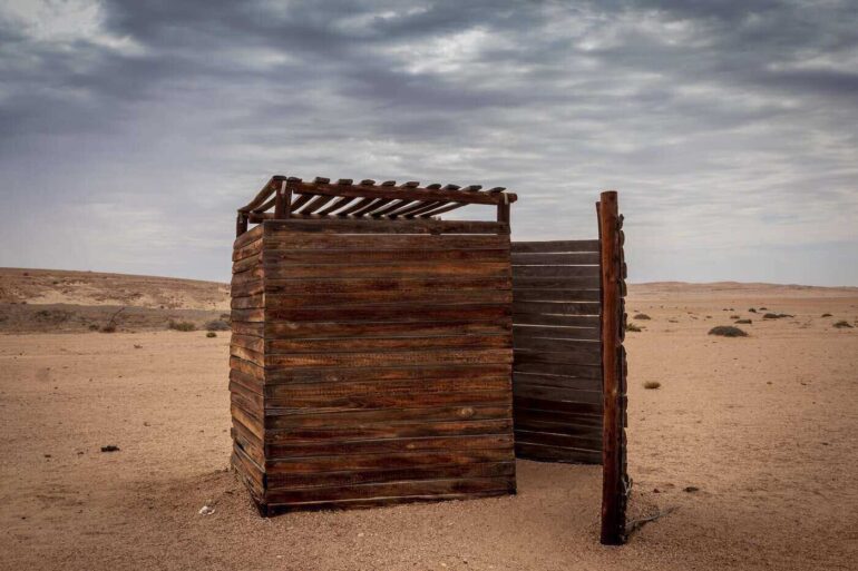 outhouse in desert under grey sky - how to build a diy composting toilet