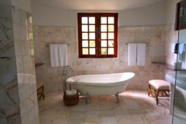clawfoot tub under wooden window - turn your bathroom into an eco-friendly sanctuary with these water efficient plumbing fixtures