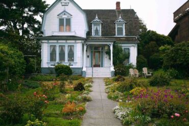 old white house with flower gardens - how to make your front yard more attractive