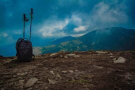 backpack and walking poles on mountain - go greener with these eco-friendly travel gadgets