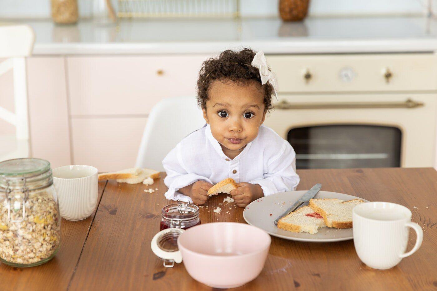 little girl eating bread at table - 7 reasons why wheat straw plates make the best dinnerware