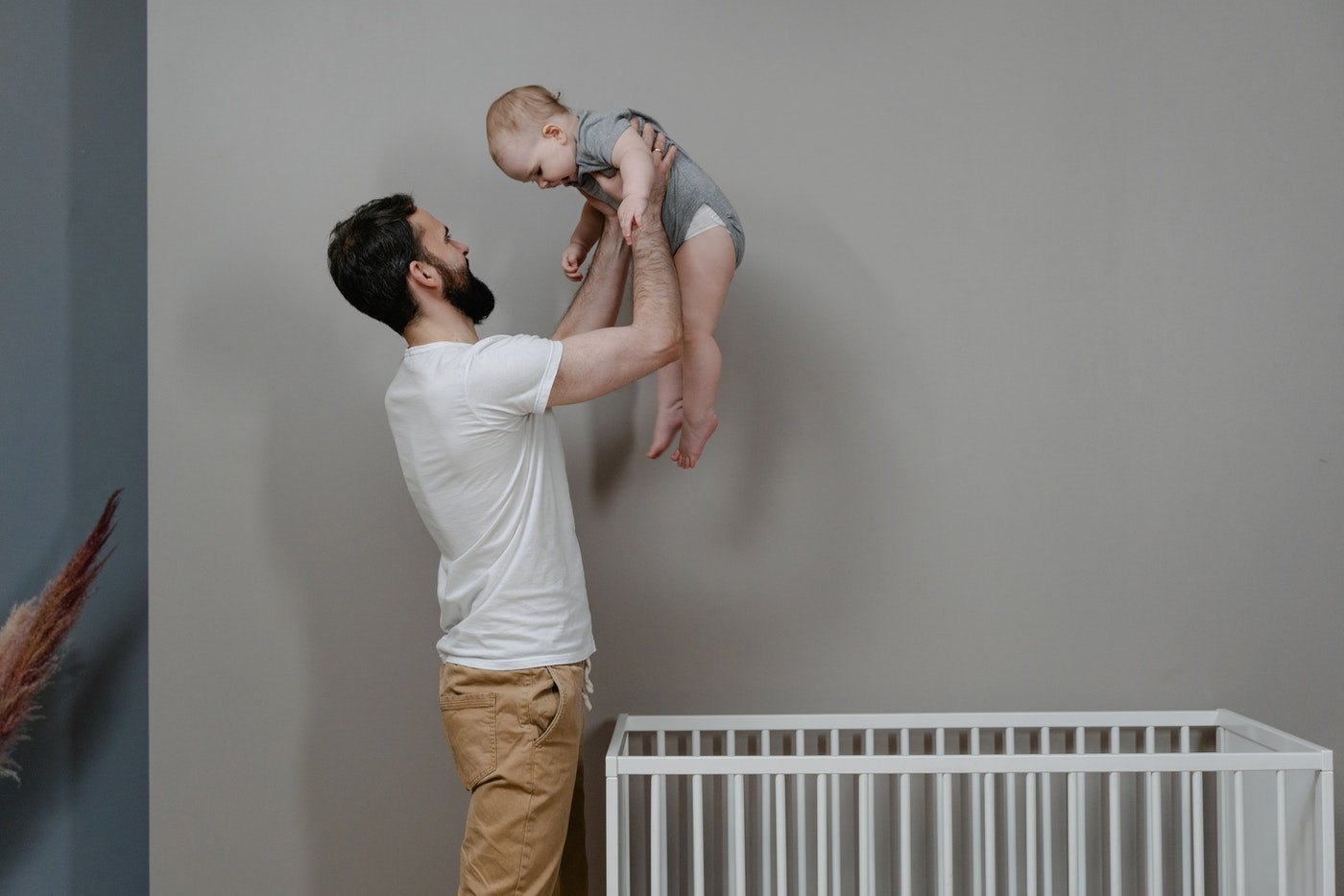 father lifting baby from crib - best baby-safe paints buying guide